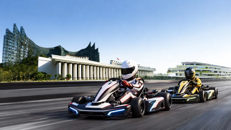 Two electric racing karts side by side on the Sumbu Timur circuit, with Istana Garuda behind them.