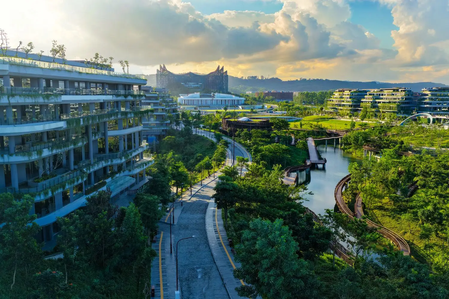 Ibu Kota Nusantara at golden hour, terraced green buildings along the river, with Istana Garuda on the ridge beyond.